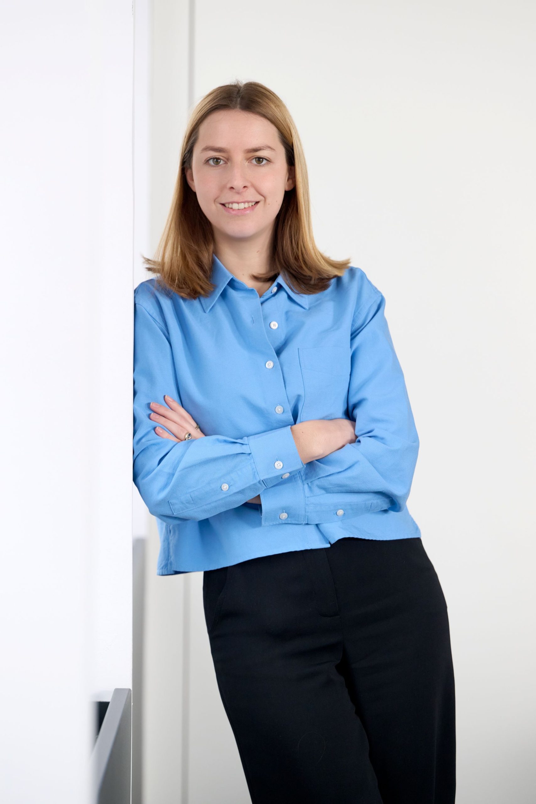 Porträt einer Businessfrau im Büro, blaue Bluse, Arme verschränkt, lächelnd